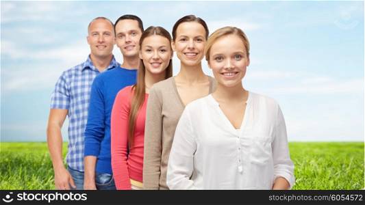 family, gender and people concept - group of smiling men and women over blue sky and grass background