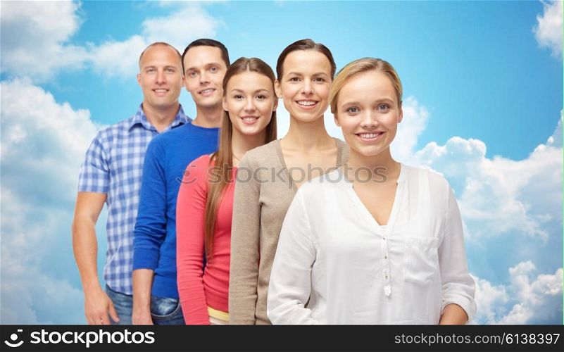 family, gender and people concept - group of smiling men and women over blue sky and clouds background
