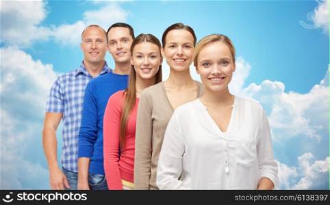 family, gender and people concept - group of smiling men and women over blue sky and clouds background