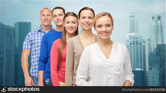family, gender and people concept - group of smiling men and women over city buildings background