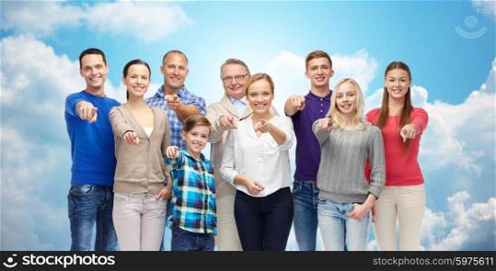 family, gender, generation and gesture concept - group of happy people pointing finger on you over blue sky and clouds background