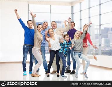 family, gender, generation and people concept - group of happy men, women and boy having fun and waving hands over empty office room or home