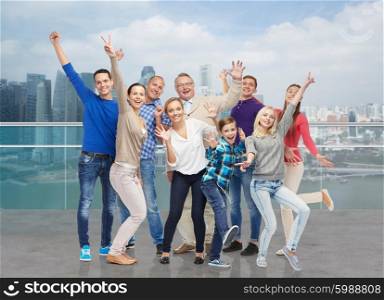 family, gender, generation and people concept - group of happy men, women and boy having fun and waving hands over singapore city waterside background