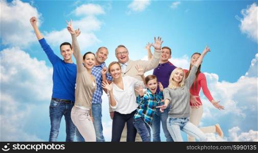 family, gender, generation and people concept - group of happy men, women and boy having fun and waving hands over blue sky and clouds background