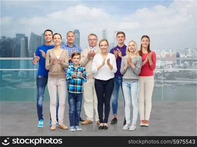 family, gender, generation and people concept - group of smiling men, women and boy applauding over singapore city waterside background