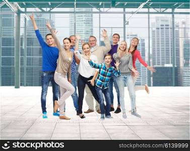 family, gender, generation and people concept - group of smiling men, women and boy having fun and waving hands over terminal with window city view background