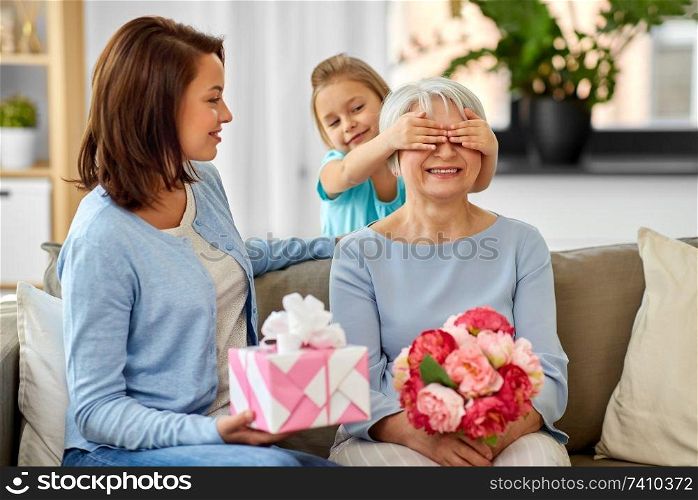 family, generation and birthday - mother and daughter greeting happy grandmother at home. mother and daughter greeting grandmother at home