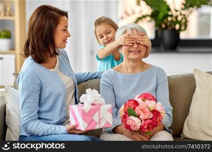 family, generation and birthday - mother and daughter greeting happy grandmother at home. mother and daughter greeting grandmother at home
