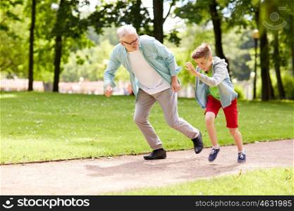 family, generation and people concept - happy grandfather and grandson racing at summer park