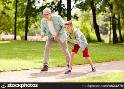 family, generation and people concept - happy grandfather and grandson racing at summer park