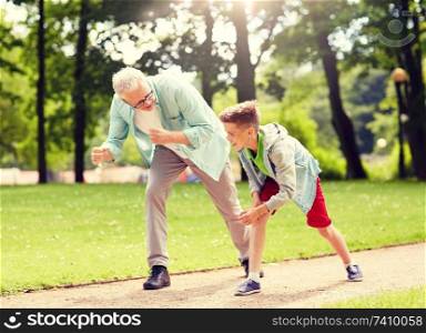family, generation and people concept - happy grandfather and grandson racing at summer park. grandfather and grandson racing at summer park