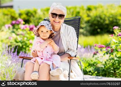 family, generation and people concept - happy grandmother with baby granddaughter at summer garden. happy grandmother and baby granddaughter at garden