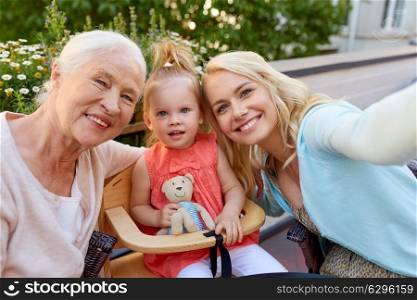 family, generation and people concept - happy mother, daughter and grandmother taking selfie at cafe or restaurant terrace. happy family taking selfie at cafe