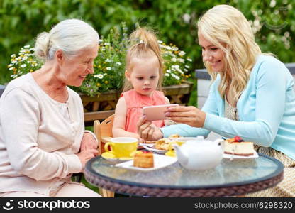 family, generation and people concept - happy mother, daughter and grandmother taking selfie by smartphone at cafe or restaurant terrace. happy family taking selfie at cafe