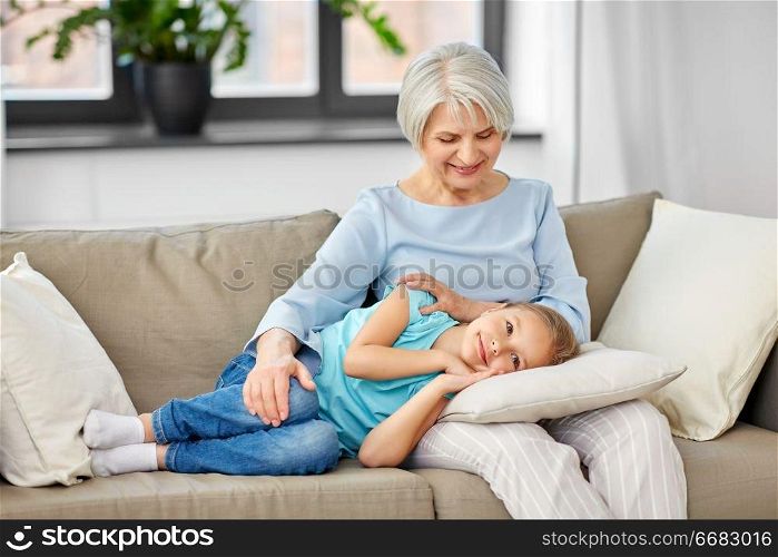 family, generation and people concept - happy smiling grandmother and granddaughter resting on pillow at home. grandmother and granddaughter resting on pillow