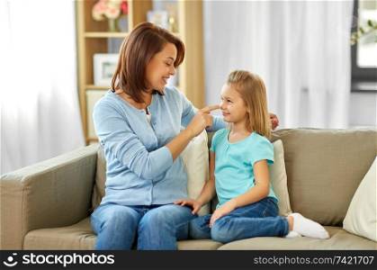 family, generation and people concept - happy smiling mother and daughter sitting on sofa at home. mother and daughter sitting on sofa at home