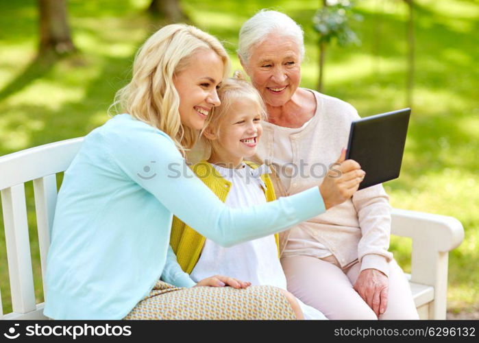 family, generation and people concept - happy smiling mother with daughter and grandmother with tablet pc computer at park. mother with daughter and grandmother at park