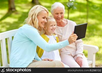 family, generation and people concept - happy smiling mother with daughter and grandmother with tablet pc computer at park. mother with daughter and grandmother at park