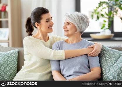family, generation and people concept - happy smiling senior mother with adult daughter hugging at home. senior mother with adult daughter hugging at home