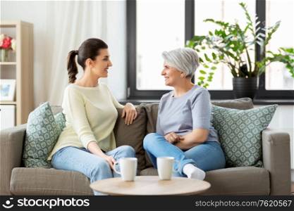 family, generation and people concept - happy smiling senior mother with adult daughter talking at home. senior mother with adult daughter talking at home