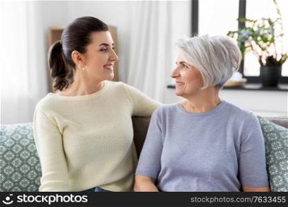 family, generation and people concept - happy smiling senior mother with adult daughter talking at home. senior mother with adult daughter talking at home