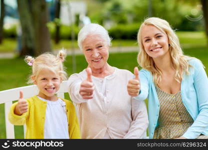 family, generation and people concept - happy smiling woman with daughter and senior mother sitting on park bench. woman with daughter and senior mother at park