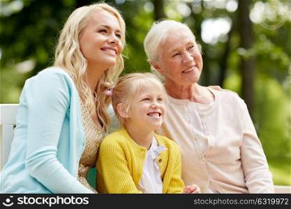 family, generation and people concept - happy smiling woman with daughter and senior mother sitting on park bench. woman with daughter and senior mother at park