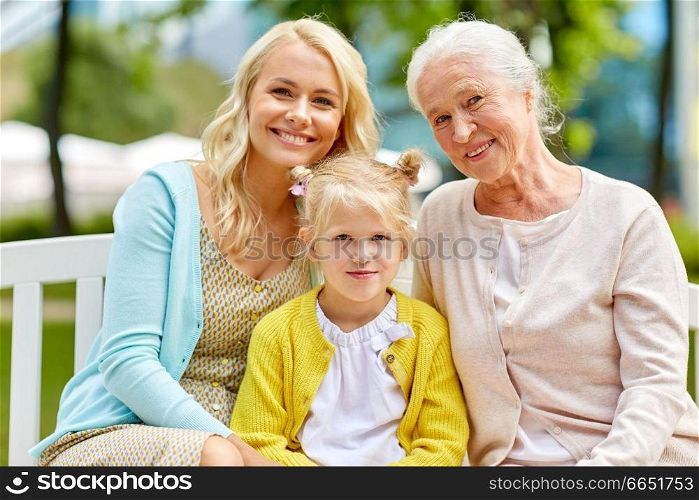 family, generation and people concept - happy smiling woman with daughter and senior mother sitting on park bench. woman with daughter and senior mother at park