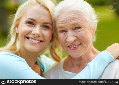 family, generation and people concept - happy smiling young daughter with senior mother sitting on park bench and hugging. daughter with senior mother hugging on park bench