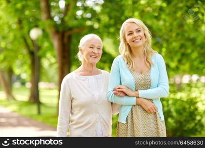 family, generation and people concept - happy smiling young daughter with senior mother at park. daughter with senior mother at park