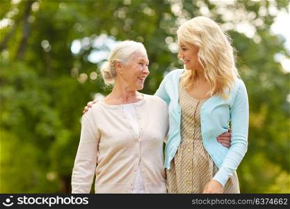 family, generation and people concept - happy smiling young daughter with senior mother hugging at park. daughter with senior mother hugging at park