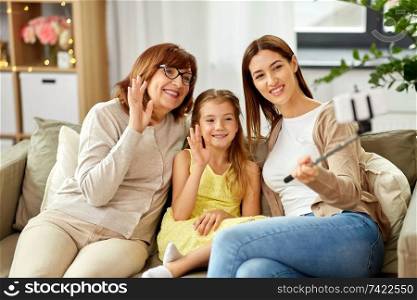 family, generation and technology concept - happy mother, daughter and grandmother taking picture by selfie stick at home. mother, daughter and grandmother taking selfie