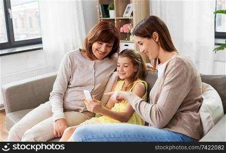 family, generation and technology concept - happy mother, daughter and grandmother with smartphone at home. mother, daughter and grandmother with smartphone