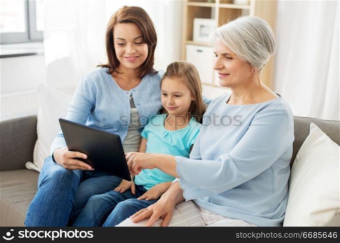 family, generation and technology concept - happy mother, daughter and grandmother with tablet computer at home. mother, daughter and grandmother with tablet pc