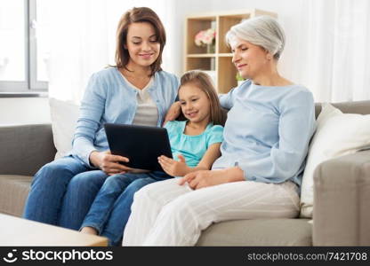 family, generation and technology concept - happy mother, daughter and grandmother with tablet computer at home. mother, daughter and grandmother with tablet pc