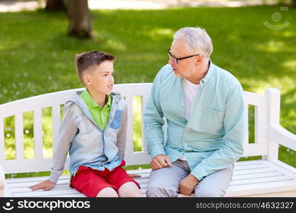 family, generation, communication and people concept - grandfather and grandson talking at summer park