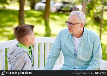 family, generation, communication and people concept - grandfather and grandson talking at summer park
