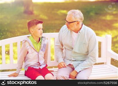 family, generation, communication and people concept - grandfather and grandson talking at summer park. grandfather and grandson talking at summer park