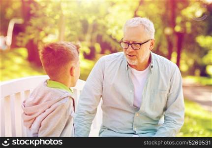family, generation, communication and people concept - grandfather and grandson talking at summer park. grandfather and grandson talking at summer park