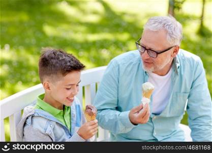 family, generation, communication and people concept - happy grandfather and grandson eating ice cream at summer park