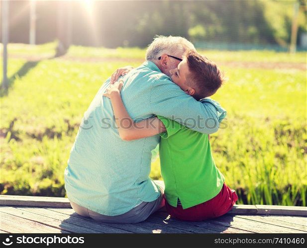 family, generation, communication and people concept - happy grandfather and grandson hugging on berth. grandfather and grandson hugging on berth