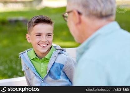 family, generation, communication and people concept - happy grandfather and grandson talking at summer park