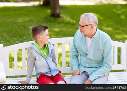 family, generation, communication and people concept - happy grandfather and grandson talking at summer park