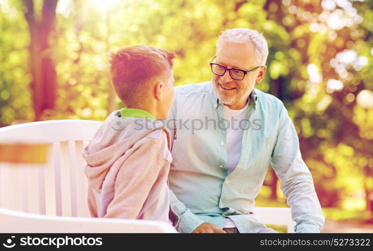 family, generation, communication and people concept - happy grandfather and grandson talking at summer park. grandfather and grandson talking at summer park