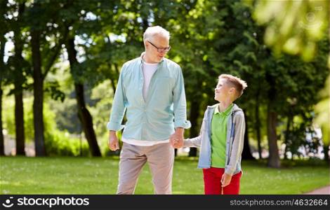 family, generation, communication and people concept - happy grandfather and grandson walking at summer park