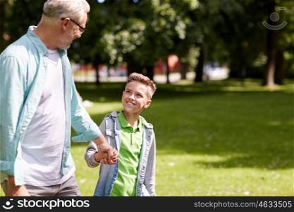 family, generation, communication and people concept - happy grandfather and grandson walking at summer park