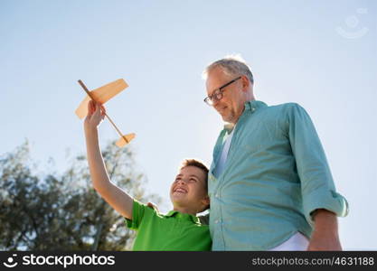 family, generation, future, dream and people concept - happy grandfather and grandson with toy airplane over blue sky