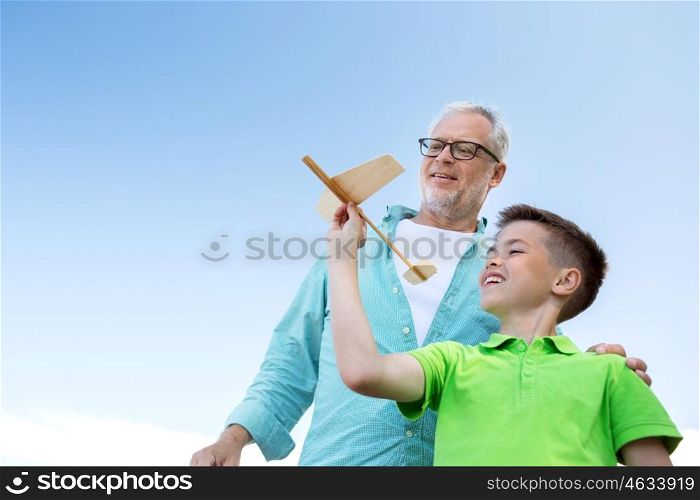 family, generation, future, dream and people concept - happy grandfather and grandson with toy airplane over blue sky