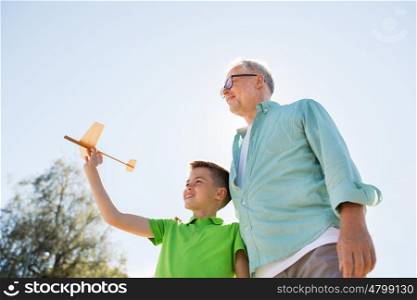 family, generation, future, dream and people concept - happy grandfather and grandson with toy airplane over blue sky