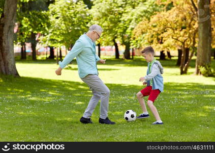 family, generation, game, sport and people concept - happy grandfather and grandson playing football at summer park